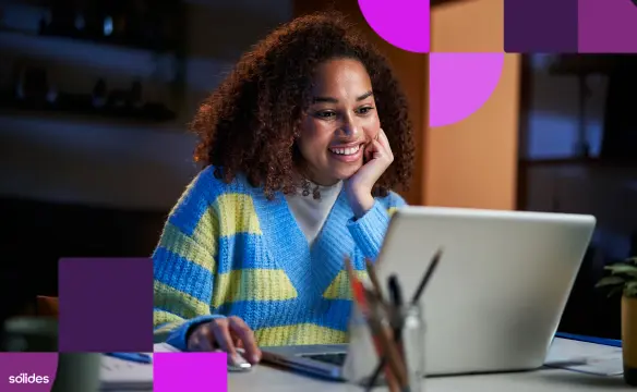 Jovem mulher sorrindo enquanto pesquisa vagas de estágio em TI no notebook