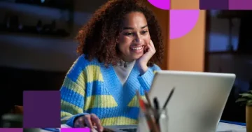 Jovem mulher sorrindo enquanto pesquisa vagas de estágio em TI no notebook